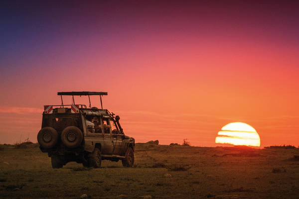 867352940 Safari Vehicle Driving Into Sunrise at Masai Mara, Kenya